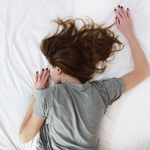thin girl sleeping face down on a bed