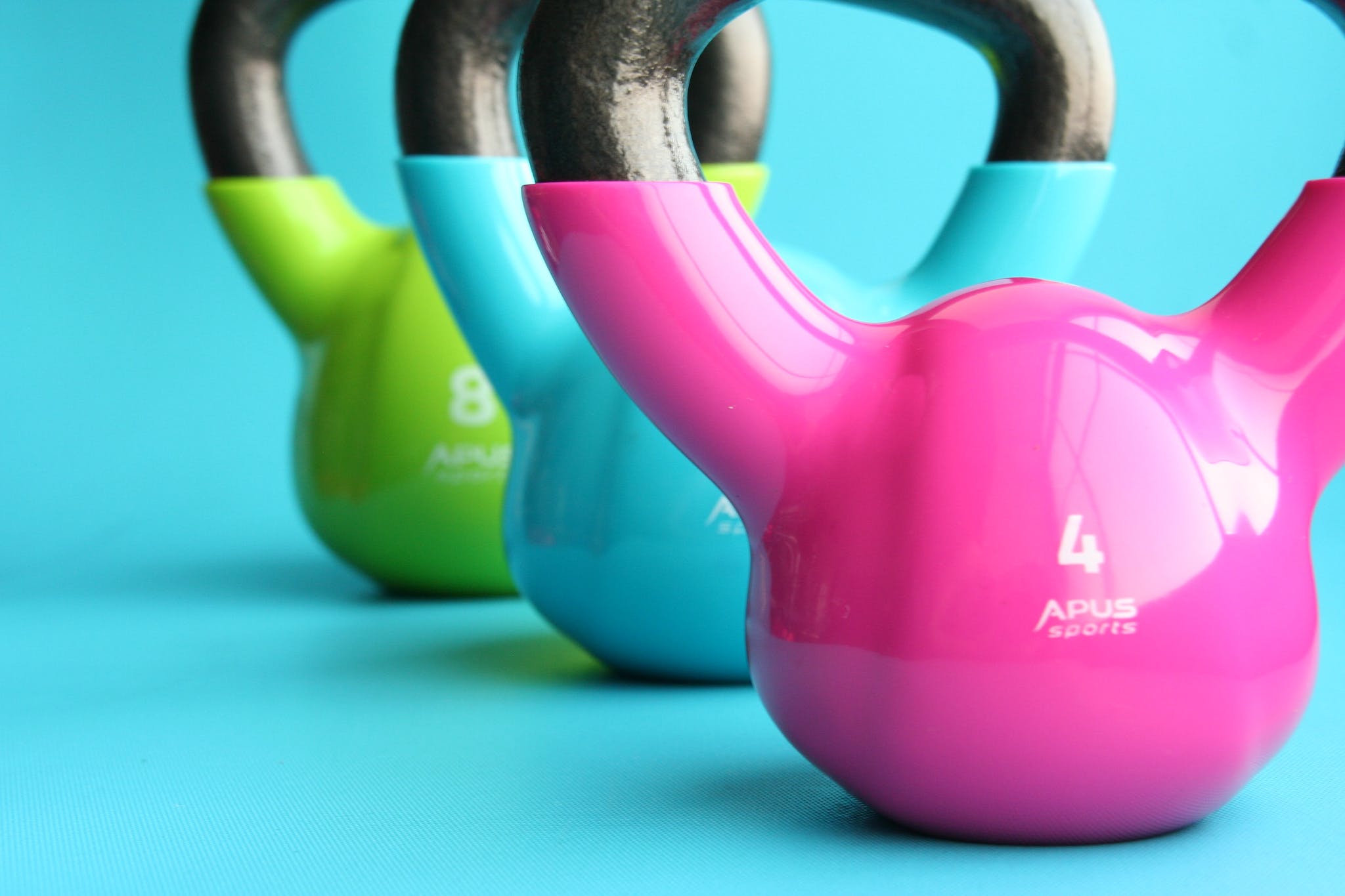 Green, Blue, and Pink Kettle Bells on Blue Surface